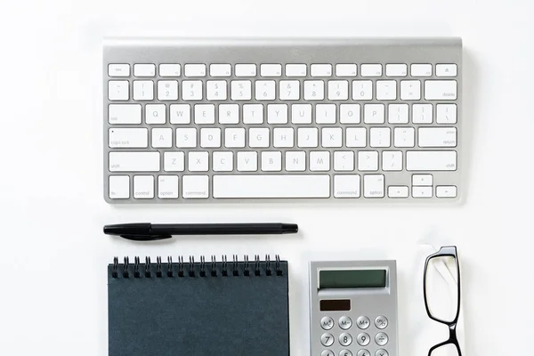Still life of accountant workspace with office accessories. Flat lay white desk with computer keyboard, calculator and notepad. Accounting and banking services. Finance and investment concept.