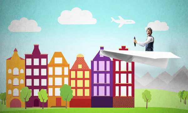 Man in aviator helmet sitting in paper plane and flying above town. Pilot driving paper plane on background of cartoon city. Cityscape with green grass and cute houses. Dreaming and imagination.