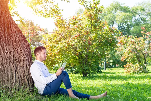 Молодой Человек Использует Планшетный Компьютер Деревом Парке Солнечный День Красивый — стоковое фото