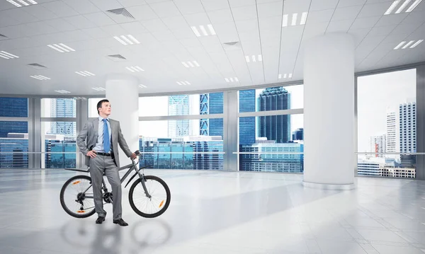 Χαμογελαστός Άντρας Στο Επιχειρηματικό Κοστούμι Στέκεται Ποδήλατο Στην Άνετη Αίθουσα — Φωτογραφία Αρχείου