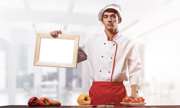 Jovem Chef Perto Mesa Cozinhar Segurando Placa Branca Branco Bonito — Fotografia de Stock