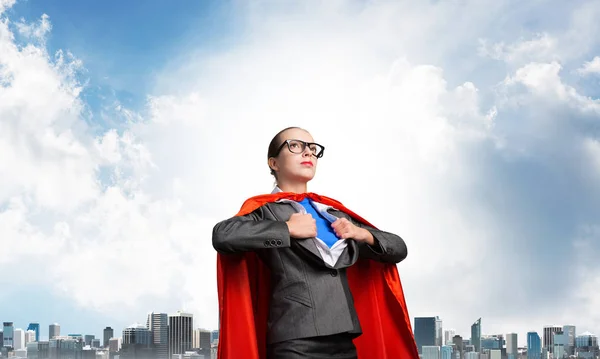 严肃的女商人穿着红色英雄斗篷 蓝天和都市风貌背景 商业女性的肖像超级女主人公 专业风险管理 勇敢的超级女人准备迎接新的挑战 — 图库照片