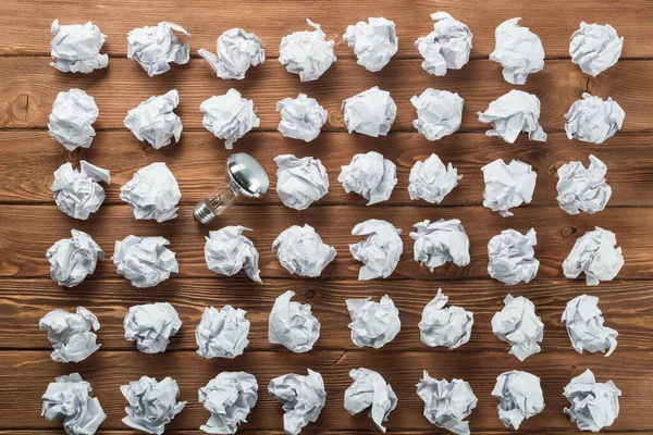 Bombilla Incandescente Bolas Papel Blanco Arrugadas Sobre Mesa Madera Marrón —  Fotos de Stock