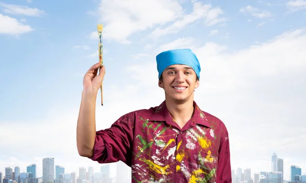 Joven Pintor Sonriente Apuntando Hacia Arriba Con Pincel Mano Retrato —  Fotos de Stock