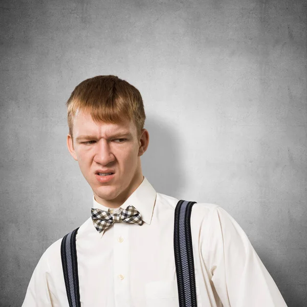 多么恶心 不高兴的红头发嬉皮士 喜怒无常的男孩看到令人厌恶或厌恶的事情时 脸上都会流露出不满意的表情 穿着白衬衫 领结和吊带衫的人的画像 — 图库照片