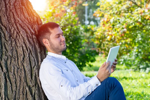 Mladý Muž Používá Tablet Pod Stromem Parku Slunečného Dne Hezký — Stock fotografie