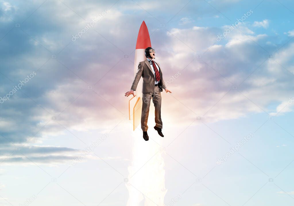 Businessman in suit and aviator hat flying on rocket in stratosphere. Superhero businessman flying with jetpack rocket in blue sky above clouds. Successful business startup. Career growth concept.