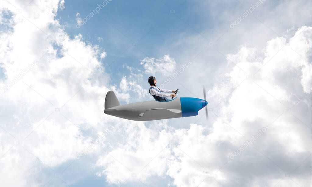 Man in aviator hat with goggles driving propeller plane. Funny man having fun in small airplane. Blue cloudy sky with fluffy clouds. Businessman sitting in paper plane and holding steering wheel.