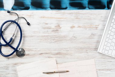 Doktorlar tıbbi malzemelerle birlikte masaüstünde. Bilgisayar klavyesi, x-ışını görüntüsü, steteskop ve kardiyogram tahta masada. Fotokopi alanı ile sağlık teknolojisi kavramı. Tıbbi danışma ve tedavi