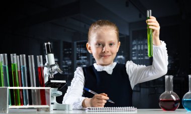 Küçük bilim adamı kız deney tüpünü kimyasal reaktörle inceliyor. Okulda araştırma ve eğitim. Mikroskop ve cam mataralı kimya laboratuvarı. Öğrenci kız kimya dersinde deney yapıyor.