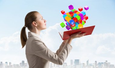 Kadın açık kitabın üzerinde uçan renkli 3D küplere bakıyor. Sanal gerçeklik soyut kare elementi olan yüksek teknoloji konsepti. Açık kitabı olan bir iş kadını. Şehir merkezindeki iş geçmişinde zarif bir bayan.
