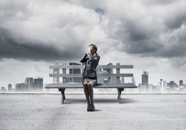 Dışarıdaki ahşap bankta oturan genç kadın. İş elbiseli bir kız, sürpriz yapmak için ellerini yüzüne koyar. Sorunlardan saklanın. Yardım ve başarılı çözümler. Fırtınalı gökyüzü ile modern şehir manzarası.