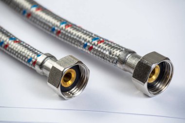 İç vida bağlayan su örgülü metal hortum. Esnek hidrolik sistemi kapatın. Sıhhi tesisat boru hattı masaya yatıyor. Banyo tamiri veya inşaat hizmeti için yeni ekipmanlar.