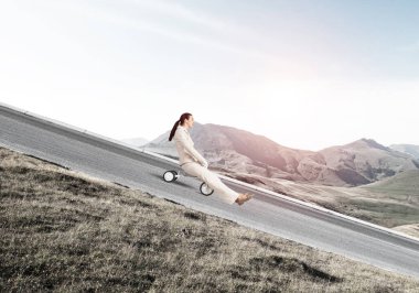 Dağ yolunda yokuş aşağı giden güzel, mutlu bir kadın. Beyaz takım elbiseli genç bir işçi dışarıda küçük bir bisiklete biniyor. Profesyonel kariyer başlangıcı. Çılgın şirket çalışanı eğleniyor..