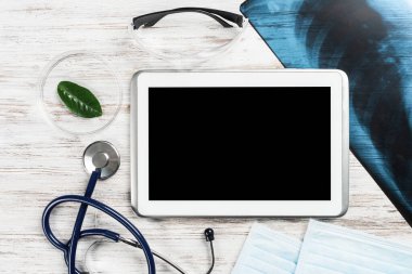 Modern hastanede tıbbi teşhisler. Tablet bilgisayarı, röntgen görüntüsü, stetoskopu olan doktor masasının üst görüntüsü. Sağlık sigortası konsepti. Profesyonel sağlık ve dijital teknoloji
