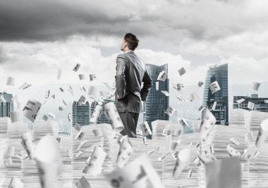 Takım elbiseli kendine güvenen işadamı arka planda şehir manzarası olan uçan gazeteler arasında doküman yığınının üzerinde duruyor. Karışık ortam.