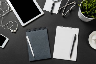 Tablet bilgisayarlı modern iş yeri manzarası. Düz kompozisyonda yeşil bitki ve siyah yüzeyde ofis malzemeleri vardı. Üst görünüm çalışma alanı stil tasarımı. Dijital teknoloji ve hareketlilik