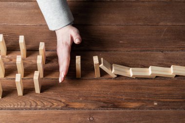 İş kadını, domino taşını engelliyor. Ticari risk yönetimi ve istikrar durumu. Masasında tahta bloklar olan bir hayat sigortası şirketi sunumu. Ekonomik krizden koruma.