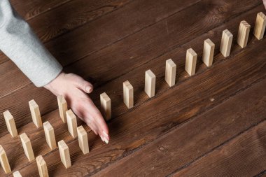 Dominoları tahta masaya düşmekten koruyan iş kadını. Kriz anında iş yardımı ve liderlik. Operatif iş çözümü ve durumun istikrar kazanması. Profesyonel risk yönetimi