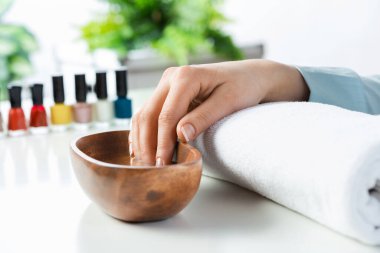 Yakın plan kadın eli su dolu ahşap bir kasede. Spa prosedürü ve rahatlama. Kadın eli maniküre hazırlanıyor. Profesyonel tırnak bakımı ve güzellik servisi. Güzellik ve hijyen kavramı