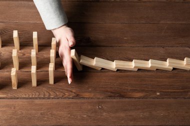 Dominoları tahta masaya düşmekten koruyan iş kadını. Kriz anında iş yardımı ve liderlik. Operatif iş çözümü ve durumun istikrar kazanması. Profesyonel risk yönetimi
