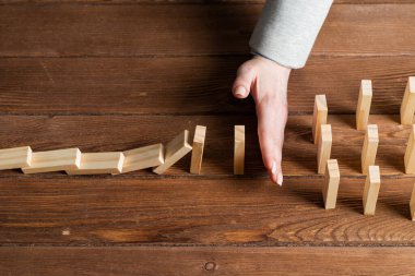 İş kadını, domino taşını engelliyor. Ticari risk yönetimi ve istikrar durumu. Masasında tahta bloklar olan bir hayat sigortası şirketi sunumu. Ekonomik krizden koruma.