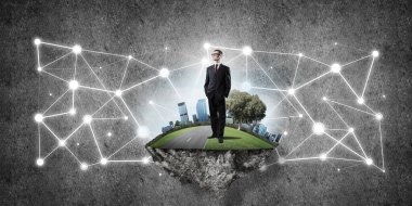 Uçan yeşil adada beton zeminde zarif bir işadamı.