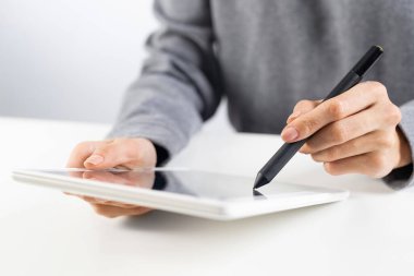 İş kadını haber okumak için tablet bilgisayar kullanıyor. Ofis masasında elinde tablet olan kadın ellerinin yakın çekimi. Çevrimiçi iş istatistikleri ve analizleri. Yenilikçi şirkette modern işyeri