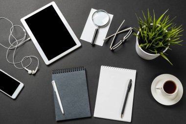 Tablet bilgisayarlı modern iş yeri manzarası. Düz kompozisyonda yeşil bitki ve siyah yüzeyde ofis malzemeleri vardı. Üst görünüm çalışma alanı stil tasarımı. Dijital teknoloji ve hareketlilik