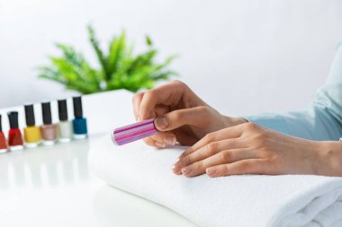 Kadın tırnak törpüsü kullanıyor ve mükemmel tırnak şekli yaratıyor. Tırnak törpüleme aleti ile kadın tırnaklarını törpülemek ve oje sürmeye hazırlanmak. Evde tırnak bakımı yapan bir kadın. Güzellik ve temizlik.