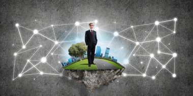 Uçan yeşil adada beton zeminde zarif bir işadamı.