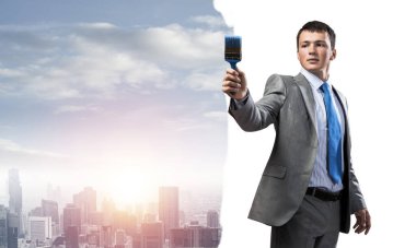 Elinde fırça tutan yaratıcı ressam gülümsüyor. Şehir planında takım elbiseli ve kravatlı neşeli yakışıklı bir adamın portresi. İş konseptinde hırs ve yaratıcılık