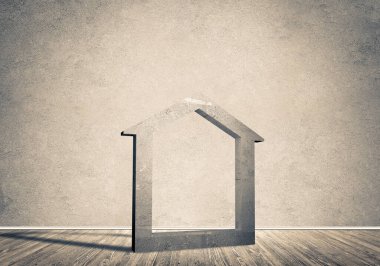 Ev taşı figürü, boş beton odadaki gayrimenkullerin sembolü.
