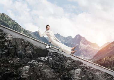 Dağ yolunda yokuş aşağı giden güzel, mutlu bir kadın. Beyaz takım elbiseli genç bir işçi dışarıda küçük bir bisiklete biniyor. Profesyonel kariyer başlangıcı. Başlangıç seviyesi iş konsepti.