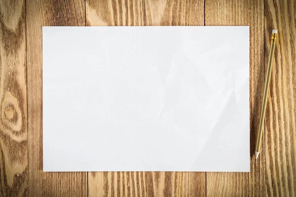 Kağıt çarşaflı düz tahta bir masa. Boş beyaz a4 format kağıdı. Yazma ve bildirim için yer var. Mesaj için dokulu doğal ahşap arka plan. Yaratıcı tasarım için klasik kopya alanı.