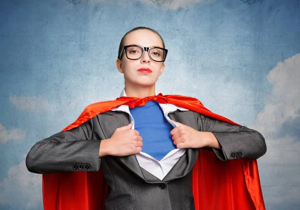 Beautiful business woman opening her shirt like a superhero. Confident lady in glasses with red hero cape. Brave super woman ready for new wins. Woman wears superhero t-shirt under her business suit.