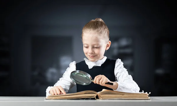 Liten Flicka Sitter Vid Skrivbordet Med Förstoringsglas Och Öppen Bok — Stockfoto