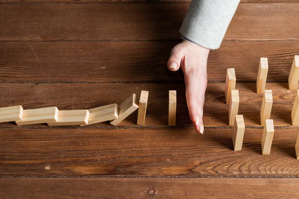 İş kadını, domino taşını engelliyor. Ticari risk yönetimi ve istikrar durumu. Masasında tahta bloklar olan bir hayat sigortası şirketi sunumu. Ekonomik krizden koruma.