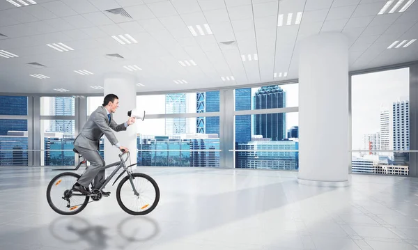Διευθυντής Στο Επιχειρηματικό Κοστούμι Που Καβαλάει Ποδήλατο Στην Αίθουσα Συνεδριάσεων — Φωτογραφία Αρχείου
