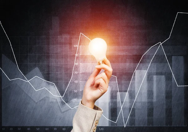 Woman Hand Holding Glowing Light Bulb Background Financial Charts Global — Stock Photo, Image