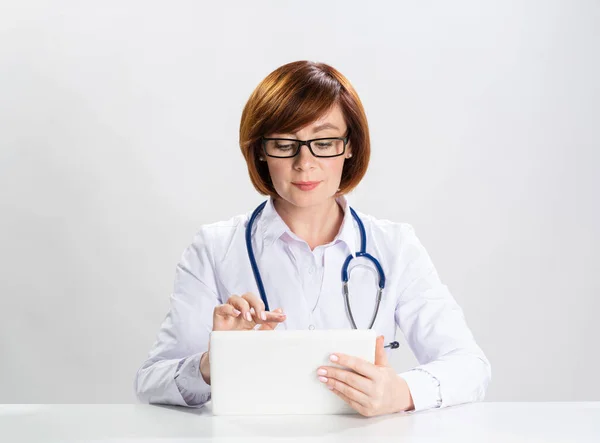 Rudowłosy Lekarz Korzystający Tabletu Biurze Lekarz Rodzinny Białym Płaszczu Stetoskopem — Zdjęcie stockowe