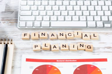 Küpler üzerine harflerle finansal planlama kavramı. Ofisteki işyerinde hala hayat var. Bilgisayar klavyesi ve analitik raporlu düz, eski bir tahta masa. Şirket geliştirme ve danışmanlık analizi.