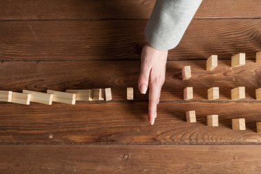 Dominoları tahta masaya düşmekten koruyan iş kadını. Kriz anında iş yardımı ve liderlik. Operatif iş çözümü ve durumun istikrar kazanması. Profesyonel risk yönetimi