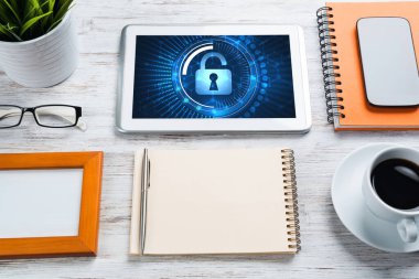 Ofis eşyalarıyla iş yeri ve ekranda asma kilit simgeleri olan tablet