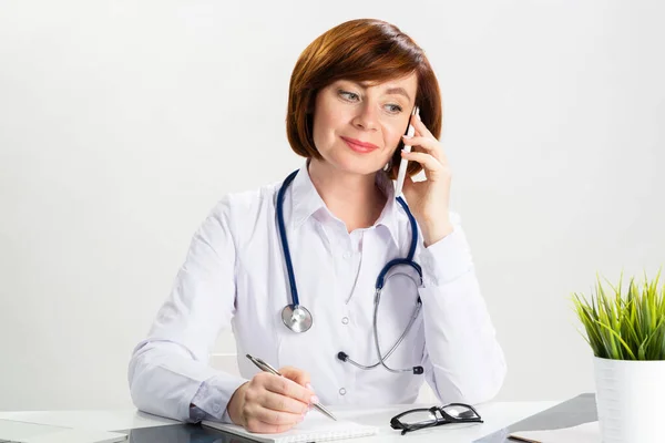 Ελκυστική Κοκκινομάλλα Γιατρός Μιλάει Στο Smartphone Στο Γραφείο Γιατρός Λευκό — Φωτογραφία Αρχείου