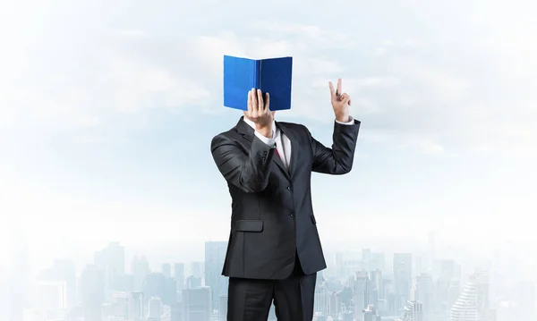 Businessman covered his face with organizer and showing fingers victory sign. Man in business suit and tie standing on cityscape background. Education and knowledges. Direction and instruction.