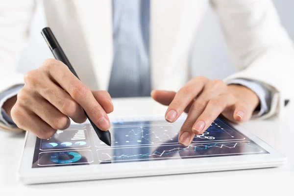 Broker in white suit using tablet computer for financial data analysis. Close-up of male hands touching screen of tablet device. Online stock trading application. Mobile smart device in business.