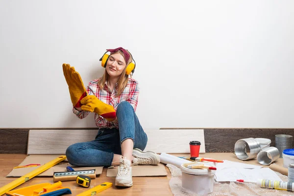 Glad Tjej Skyddande Hörlurar Och Handskar Sittande Golvet Hem Remodeling — Stockfoto