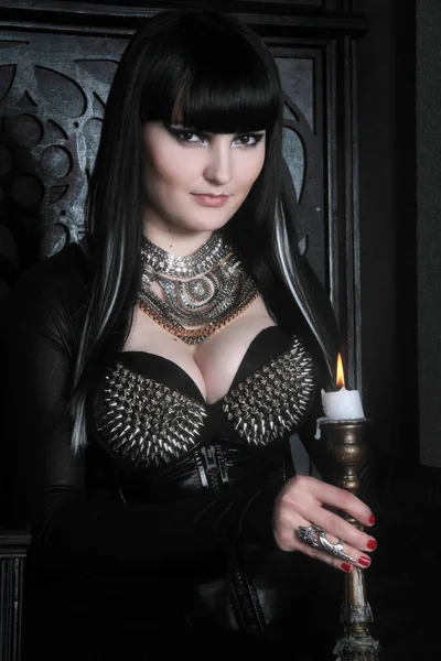 Красивая молодая готическая девушка в черном PVC и кружевной одежде позирует со свечами в старом замке — стоковое фото