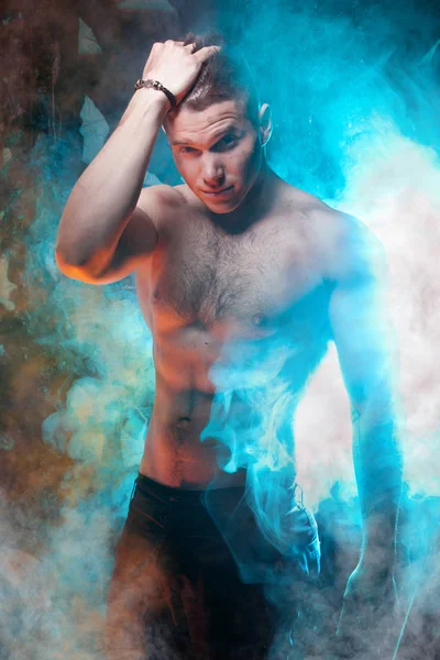 sexual young muscles man posing in the smoke